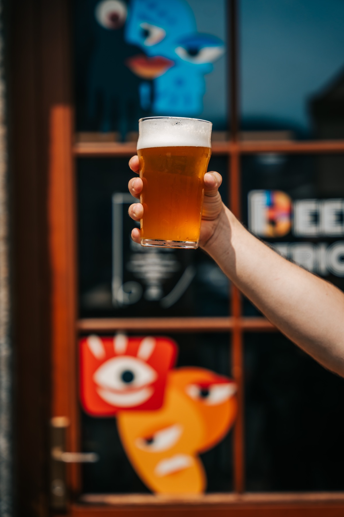 Pohár čerstvo načapovaného piva pred farebnou grafikou Beerstrice